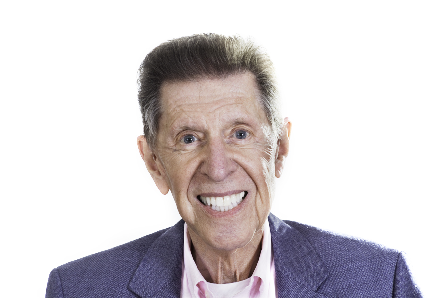 This Brian Charles Steel photo is a headshot of an older white gentleman.  He is wearing a light blue sport coat with a pink dress shirt.  He has reddish hair and blue eyes.  He is centered in the frame and the background is completely white.  He has a big smile, and he is lit with Rembrandt style lighting. 